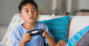 A boy sitting on the sofa holding a game console