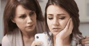 A mum and daughter look at a smartphone.