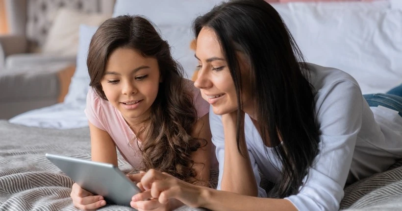 A mum and child look at a tablet together.